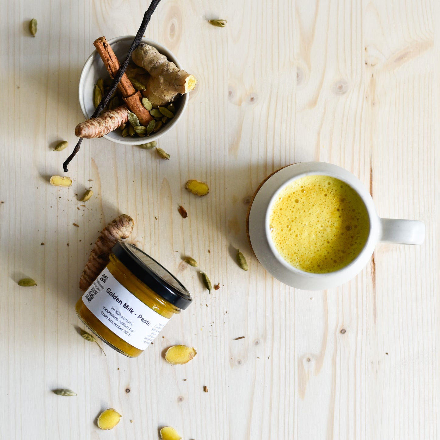 Kurkuma-Paste im Glas von oben mit Tasse Golden Milk und frischen Zutaten – handgemacht & nachhaltig verpackt